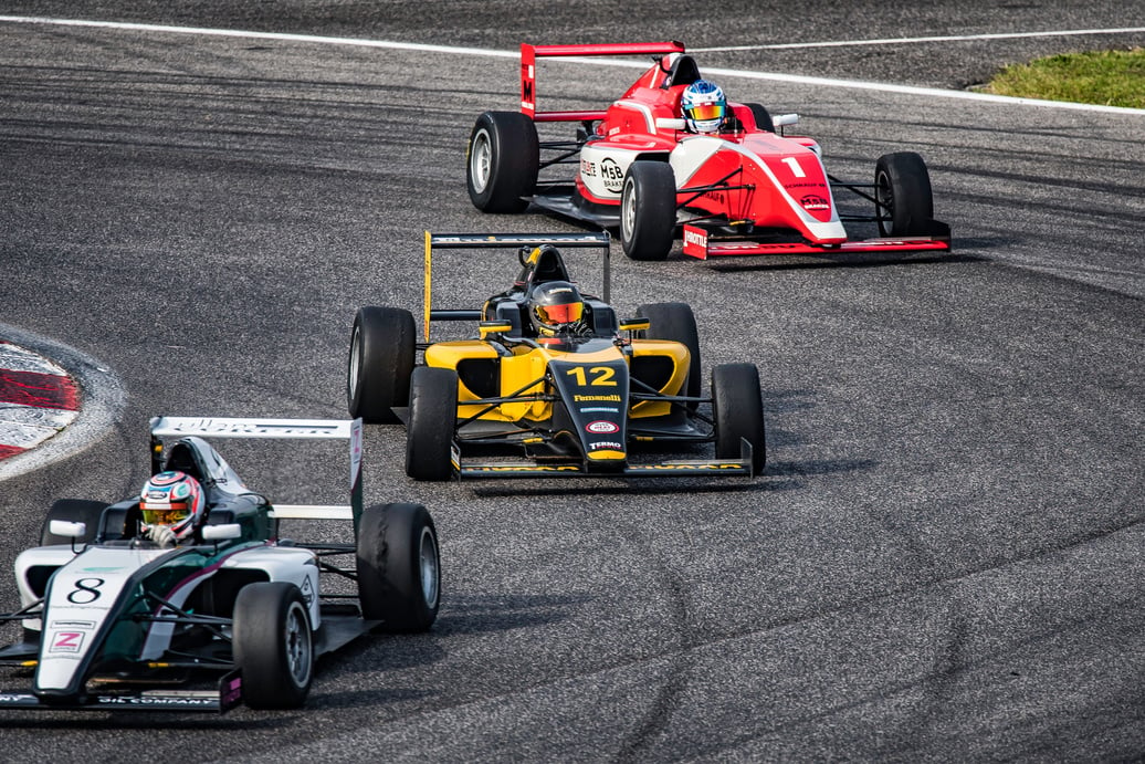 Men driving formula racing cars